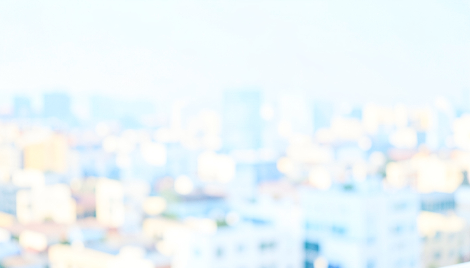 A bright, airy high-key photograph of a softly focused cityscape in pale blue and warm cream tones