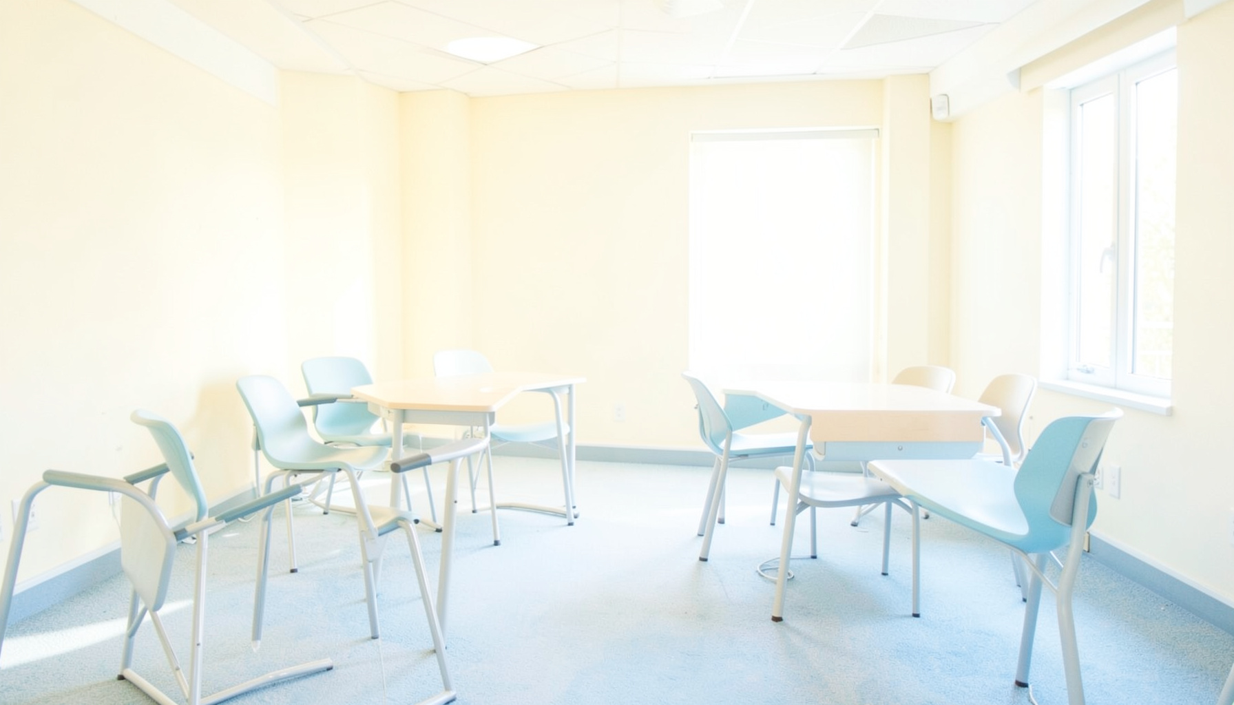 An empty discussion space bathed in soft daylight, with warm cream and pale blue tones