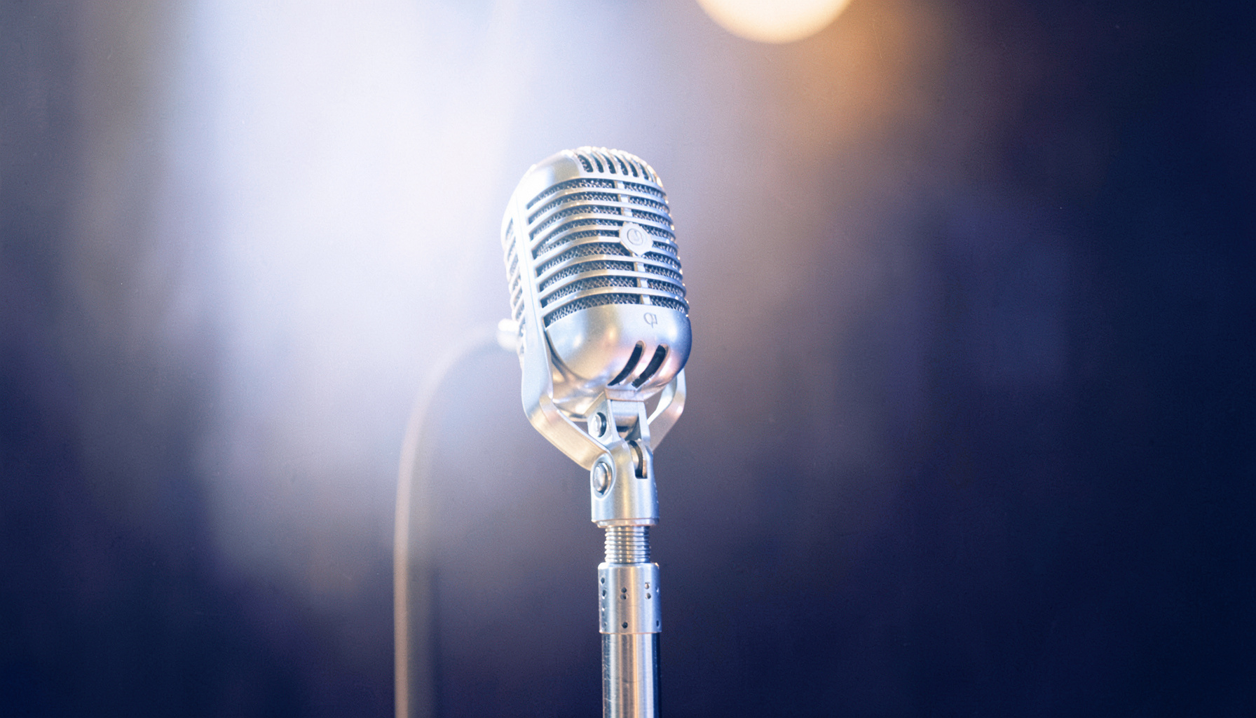 A vintage microphone on a stand in a warm studio scene, deep indigo and amber tones blending into a dark background
